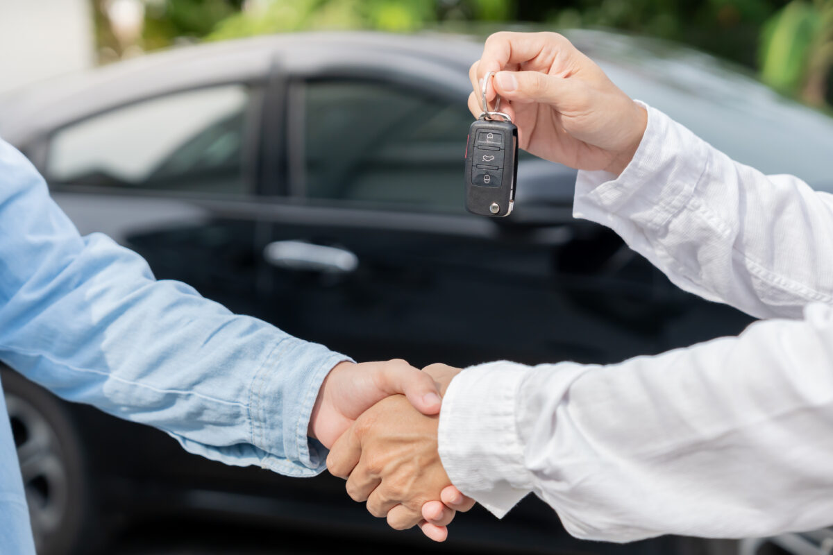 Vedoucí prodejny předává klíče od automobilu novému majiteli.