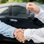 Vedoucí prodejny předává klíče od automobilu novému majiteli.