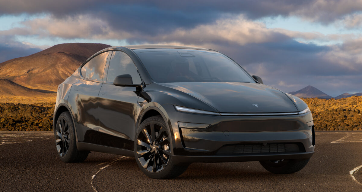 Tesla model Y v tmavě šedé barvě na pískovém podkladu s mraky v pozadí